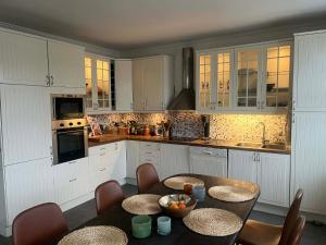 eine Küche mit weißen Schränken, einem Tisch und Stühlen in der Unterkunft Båt huset in Halmstad