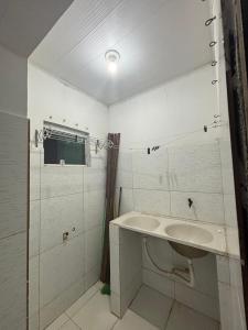 a white bathroom with a tub and a sink at Apartamento in Maragogi