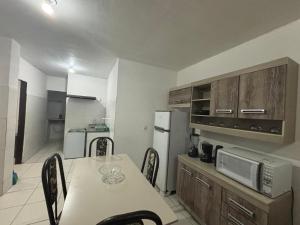 a kitchen with a table with chairs and a microwave at Apartamento in Maragogi