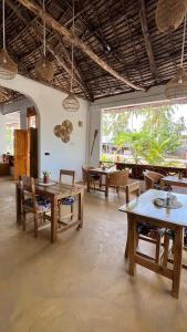 a large room with tables and chairs and windows at Palm House&Restaurant in Utende