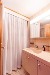 a bathroom with a sink and a white shower curtain at Ferienhaus Grundschera Engadin in Brail +30 photos