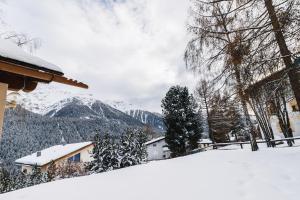 a snow covered hill with a house and mountains at Ferienhaus Grundschera Engadin in Brail