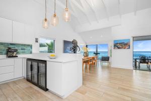 a kitchen with white counters and a dining room with the ocean at Villa View in Stompneusbaai