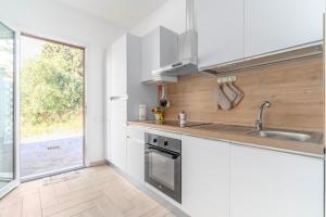 a kitchen with white cabinets and a sink and a window at New Apartment Piombino wifi parking in Piombino