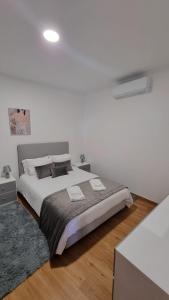 a white bedroom with a large bed and a rug at Pôr do Sol II in Porto Moniz