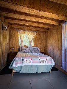 a bedroom with a large bed in a wooden room at Cabaña Santa Amelia Antuco Pet Friendly in Peluca