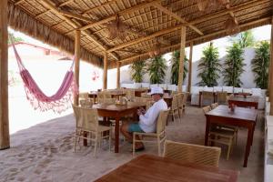 a person sitting at a table in a restaurant at Amagali Beach Club in Galinhos