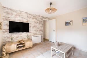 a living room with a tv on a brick wall at Le Petit Vals - Proche Casino in Vals-les-Bains