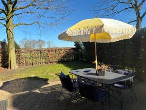 a table and chairs under an umbrella on a patio at Het Bakkers Hutje in Vortum-Mullem