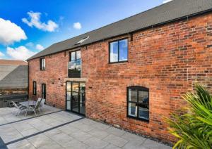a brick building with a patio in front of it at Sandstone Grange in Albrighton