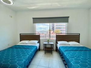two beds in a room with a window at Casa Zapopan Hotel in Guadalajara