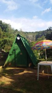 ein grünes Gebäude mit einem Sonnenschirm neben einem Tisch in der Unterkunft Caveira in Mairiporã