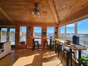 a living room with a ceiling fan and windows at Panoramic Sunrise House in Terence Bay