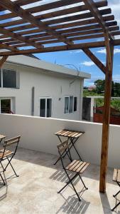 a patio with chairs and a wooden pergola at Tropical Oasis Hôtel in Vouvouni