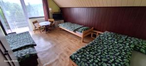 a room with two beds and a table and chairs at Agroturystyka Pod Kołami in Myczkowce