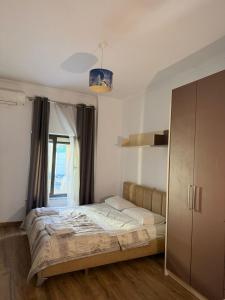 a bedroom with a bed and a window and a cabinet at Hotel La Cita in Tirana