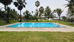 a swimming pool in a yard with palm trees at 108 Palms Beach Resort in Trincomalee