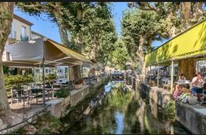 a canal in a city with tables and chairs at Le nid de Marie in Saint-André-de-Roquepertuis