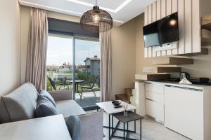 a living room with a couch and a kitchen with a window at Mulberry Suites in Paralia Dionysiou