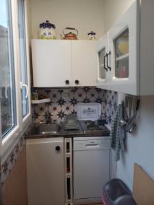 a small kitchen with white cabinets and a sink at Appartement calme in Eaux-Bonnes +3 photos