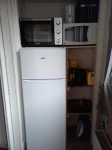 a microwave on top of a refrigerator in a kitchen at Appartement calme in Eaux-Bonnes