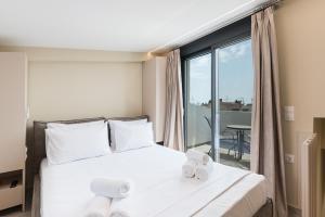 a bedroom with a bed and a balcony with a table at Mulberry Suites in Paralia Dionysiou +80 photos