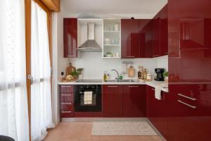 a kitchen with red cabinets and a sink at Spazio Breda - Free Parking, Private Garage, Metro M1, Balcony, 4 Guests in Milan