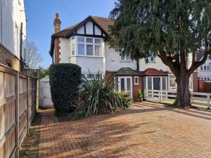 a house with a tree and a brick driveway at Osterley Room in Isleworth