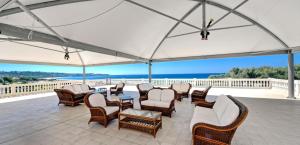 a patio with chairs and tables and a white umbrella at Santa Monica Resort in Le Castella