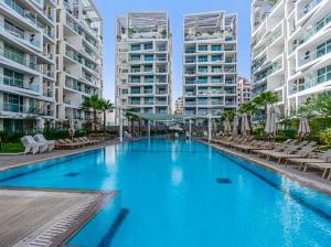 a large swimming pool with chairs and tall buildings at Redsearent suite with pool view 16 in Eilat