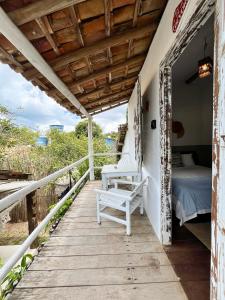 a wooden porch with a bed and a bench on it at Pousada Jardim da Praça in Caraíva