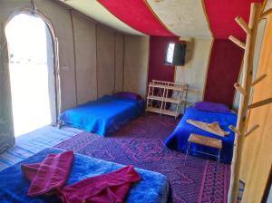 a small room with two beds and a window at Bivouac Le charme d'Aladdin in El Gouera +10 photos