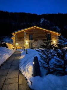 a log cabin with lights in the snow at night at Sabbionaccio Apartments & Spa in Chiesa in Valmalenco
