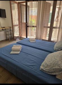 a bedroom with two beds with blue sheets and windows at House Vodice in Vodice