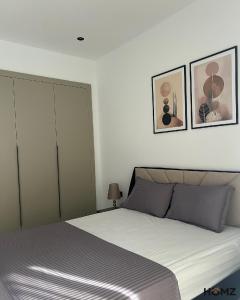 a bedroom with a bed and two pictures on the wall at Homz Maison in Sukrah +9 photos