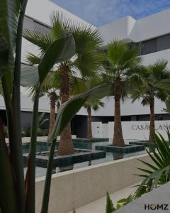 a group of palm trees in front of a building at Homz Maison in Sukrah
