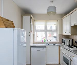 a kitchen with a white refrigerator and a window at Ocean View - 2 Bedroom Townhouse in Bundoran