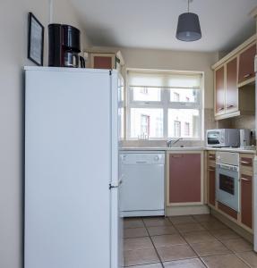 a kitchen with a white refrigerator and a window at Ocean View - 2 Bedroom Townhouse in Bundoran +4 photos