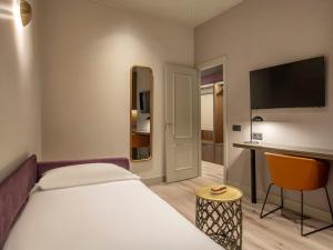 a bedroom with a bed and a desk with a television at Regente Hotel in Madrid