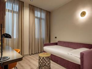 a hotel room with a couch and a window at Regente Hotel in Madrid
