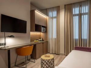 a hotel room with a bed and a desk with a television at Regente Hotel in Madrid