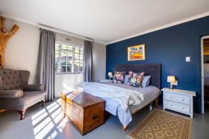 a bedroom with blue walls and a bed and a chair at Dorpsig Cottage in Paarl