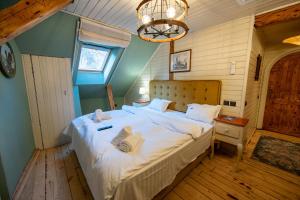 a bedroom with a bed with white sheets and a chandelier at Barrique Garden - Breakfast & Restaurant - Old Town -Officially classified guesthouse in Braşov