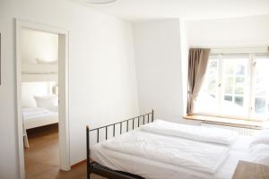 a white bedroom with a bed and a window at Stutenhof-Wohnung-06 in Keitum