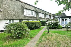a house with a thatched roof and a walkway at Stutenhof-Wohnung-06 in Keitum +3 photos