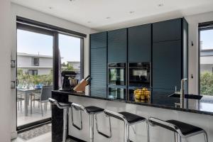 a kitchen with a black counter and stools at Harderwold Villa - 372 in Zeewolde