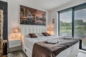 a bedroom with a bed and a large window at Harderwold Villa - 372 in Zeewolde