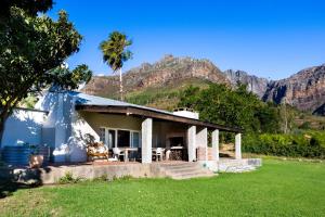 a house with a palm tree and mountains in the background at Dorpsig Cottage in Paarl
