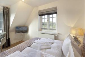 a bedroom with a white bed with a window at Listend Blick in List