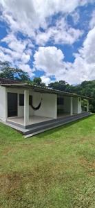 a white house with a green field in front of it at Lago Camping Sana in Macaé